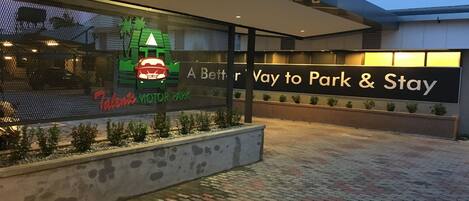 A hotel entrance with a sign reading "A Better Way to Park & Stay" and a logo for "Tabby's MOTOR PARK".