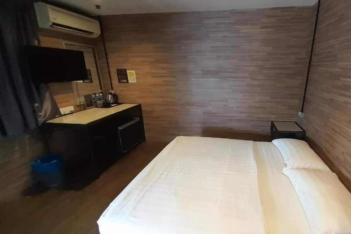 Una habitación de hotel con una cama, un tocador, un espejo y una mesita.