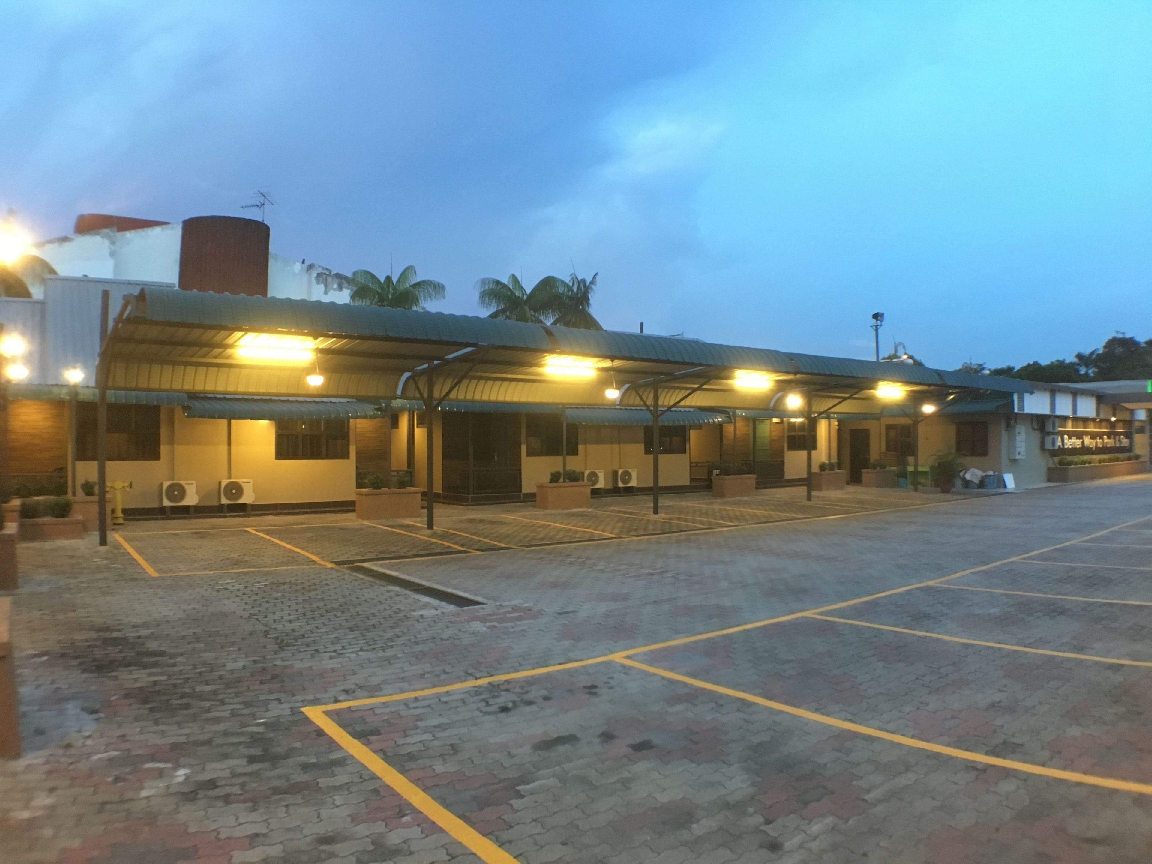 A building with multiple covered parking spaces and air conditioning units.