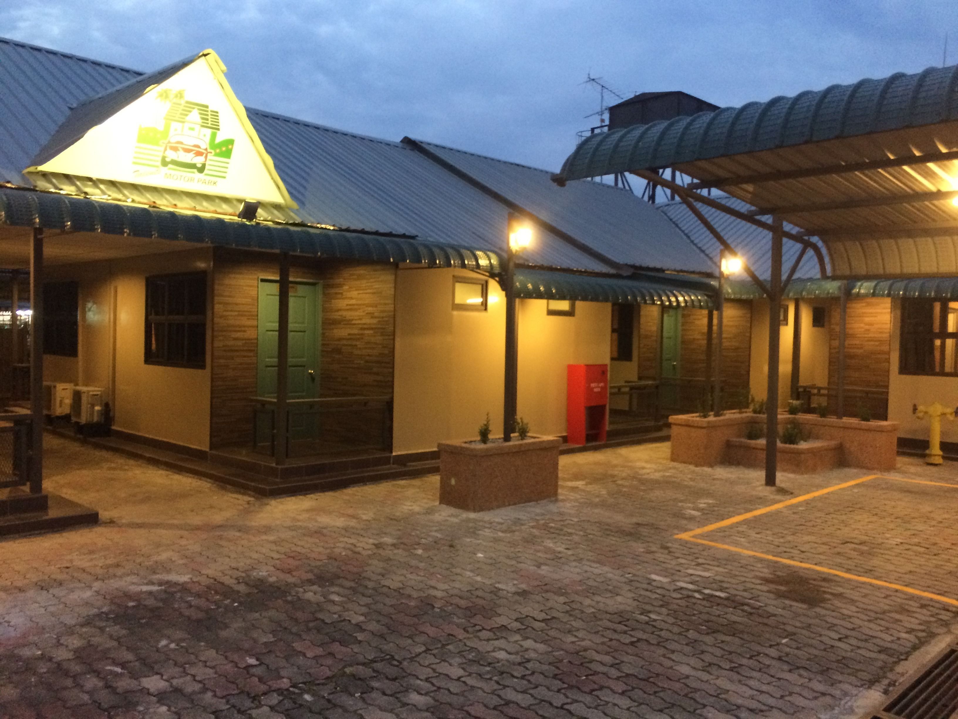 A building with a green door, a red mailbox, and a covered outdoor area with a brick floor.