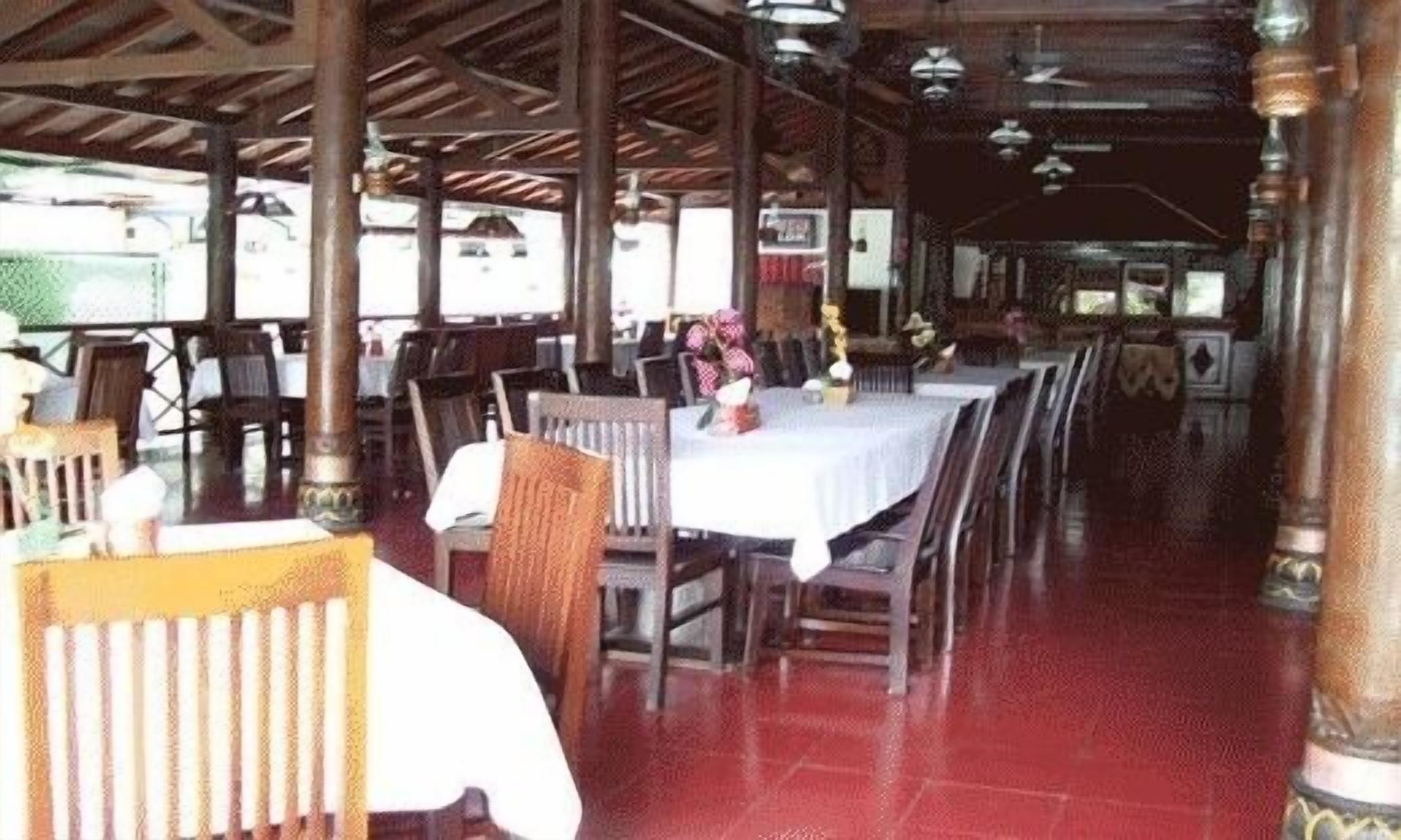 Un espace de restauration intérieur avec des tables et des chaises, un sol carrelé et un plafond avec des poutres apparentes.