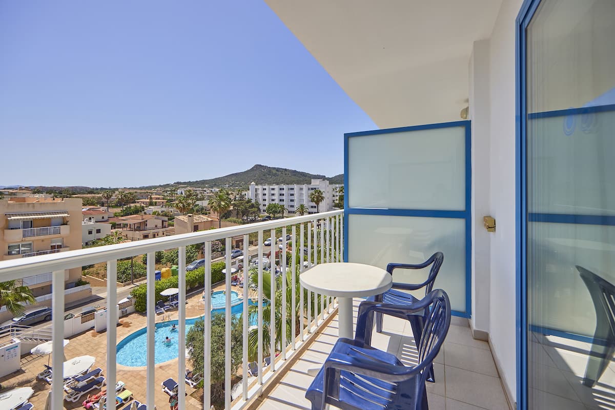 Un balcón con vista a la piscina, una mesa y sillas.