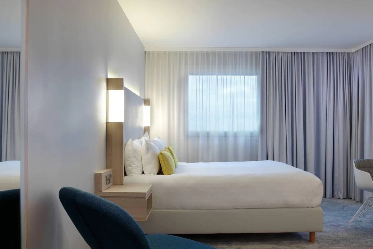 Une chambre d’hôtel moderne, équipée d’un lit, d’un bureau et d’une chaise.