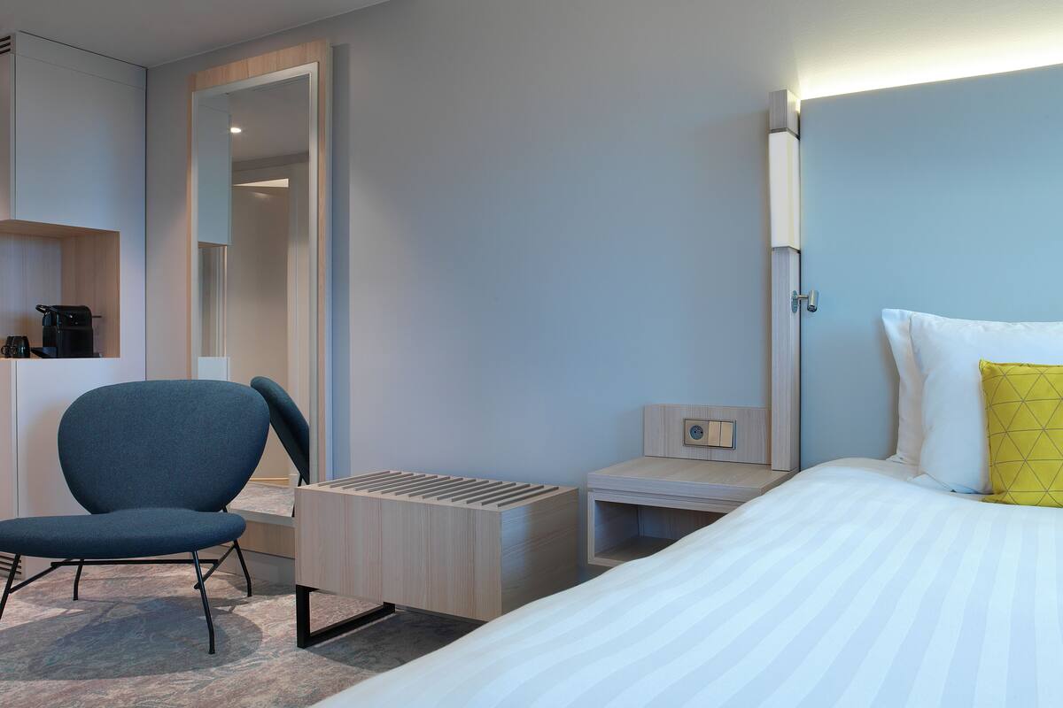 Une chambre d’hôtel avec un lit, une chaise, un bureau et une armoire.