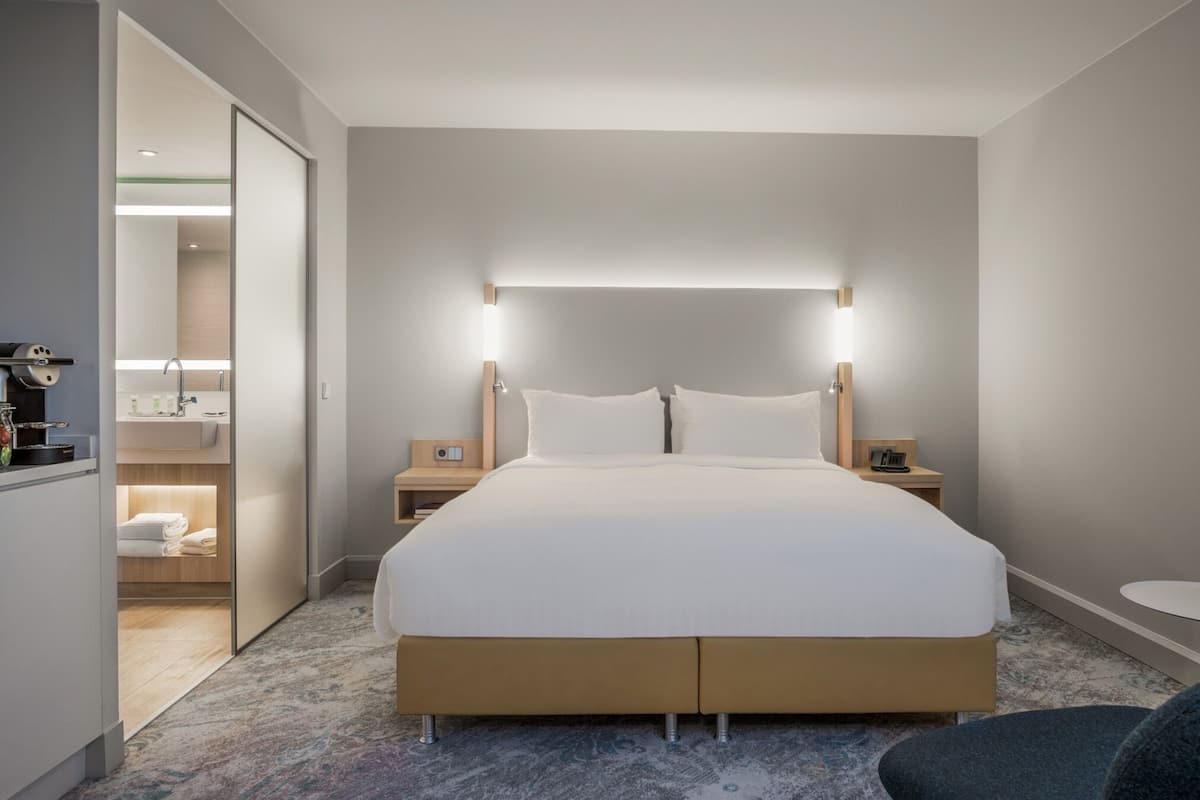 Une chambre d’hôtel avec un grand lit, des tables de chevet, une petite table de nuit, une petite table et une chaise.