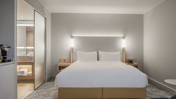 A hotel room with a large bed, bedside tables, a nightstand, a small table, and a chair.