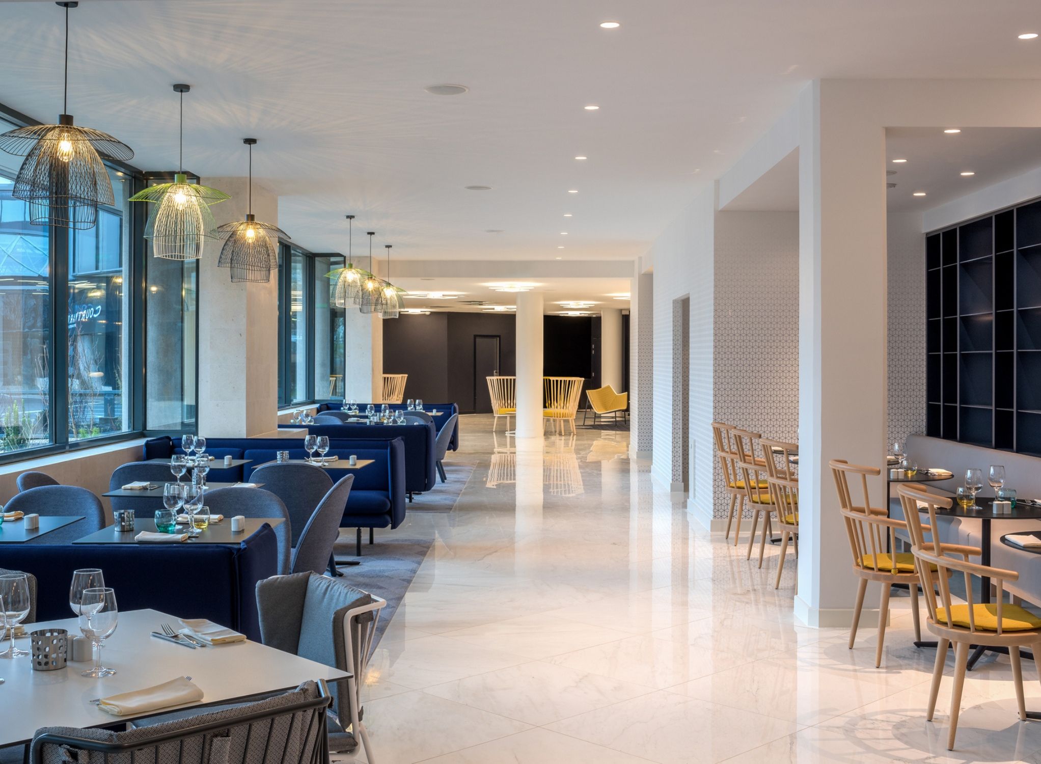 Um restaurante moderno com área de jantar extensa, assentos em cabines azuis e mesas de madeira.