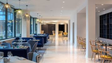 Um restaurante moderno com área de jantar extensa, assentos em cabines azuis e mesas de madeira.