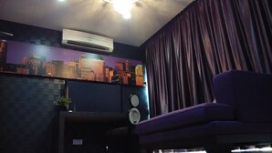 A room with a purple sofa, an air conditioner, a cityscape mural, a clock, and a curtain.