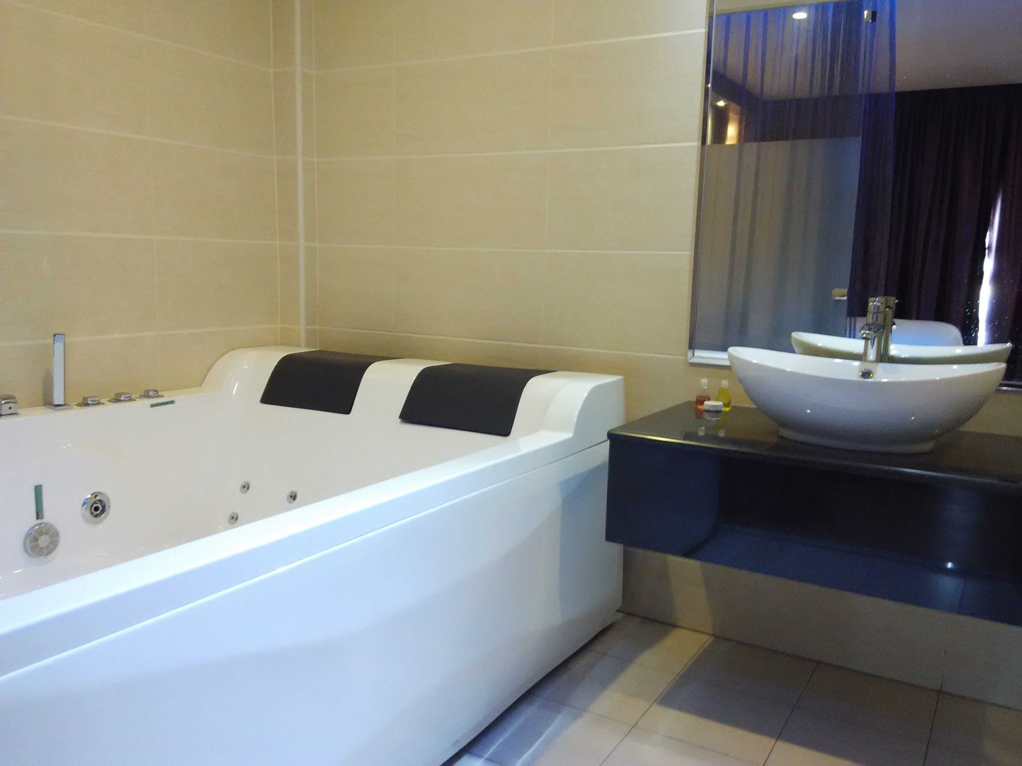 A modern bathroom with a large bathtub, a round sink, and a mirror above the sink.