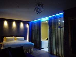 A modern hotel room with a large bed, a bathroom with a bathtub, and a chandelier. - Ampang Inn Hotel (Ampang)
