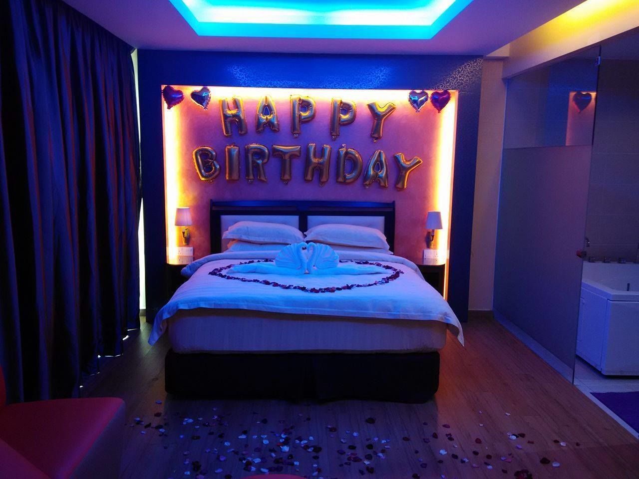 A bedroom with a bed, a 'Happy Birthday' sign, and a heart-shaped decoration on the bed.