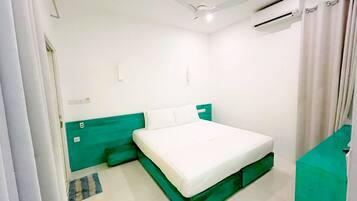 Een slaapkamer met een bed, een plafondventilator, een airconditioning en een groene accentmuur.