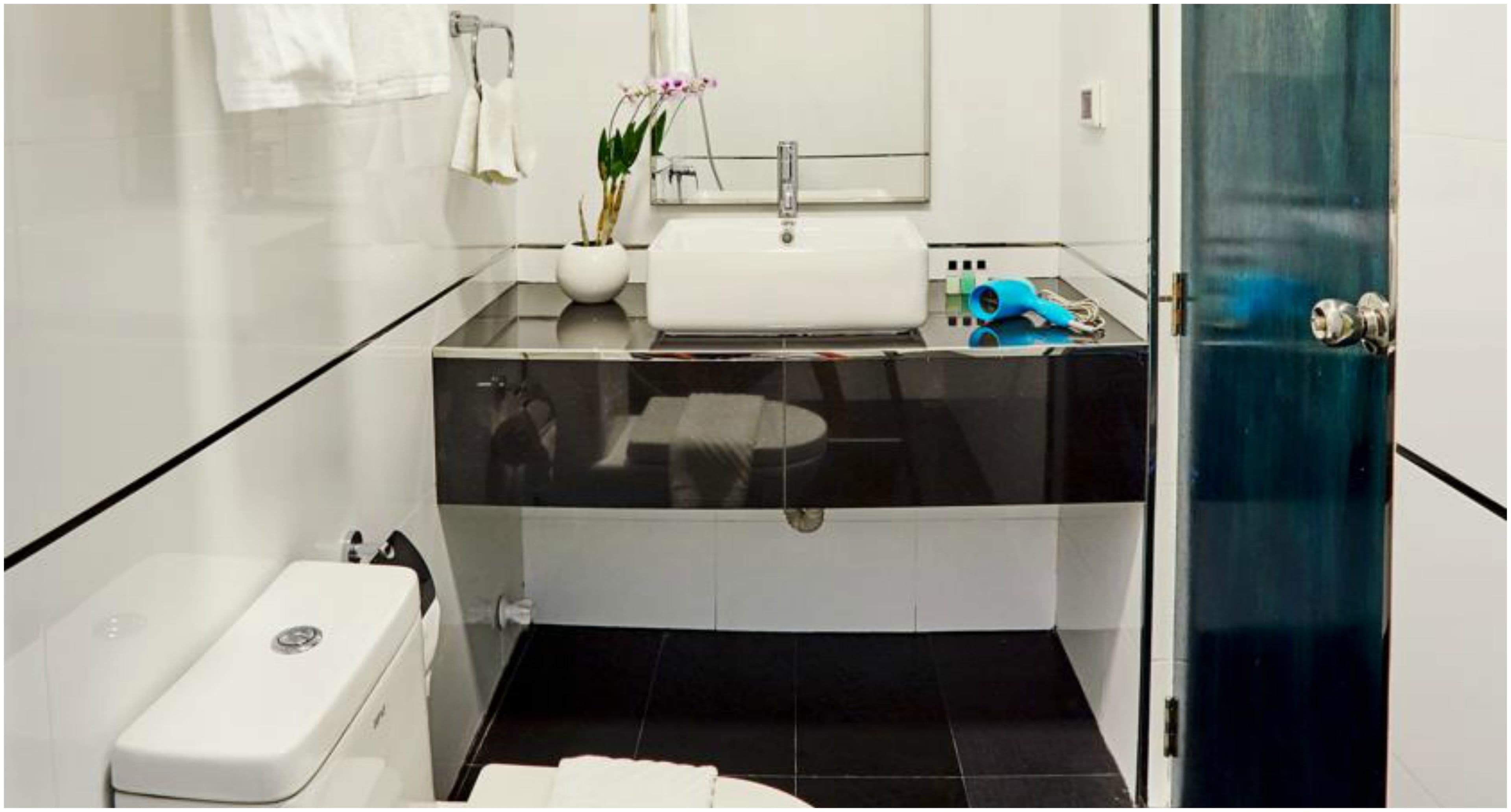 A modern bathroom with a white sink, a mirror, and a blue hairdryer on the counter.