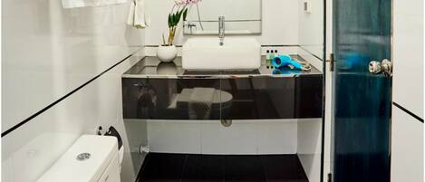 A modern bathroom with a white sink, a mirror, and a blue hairdryer on the counter.