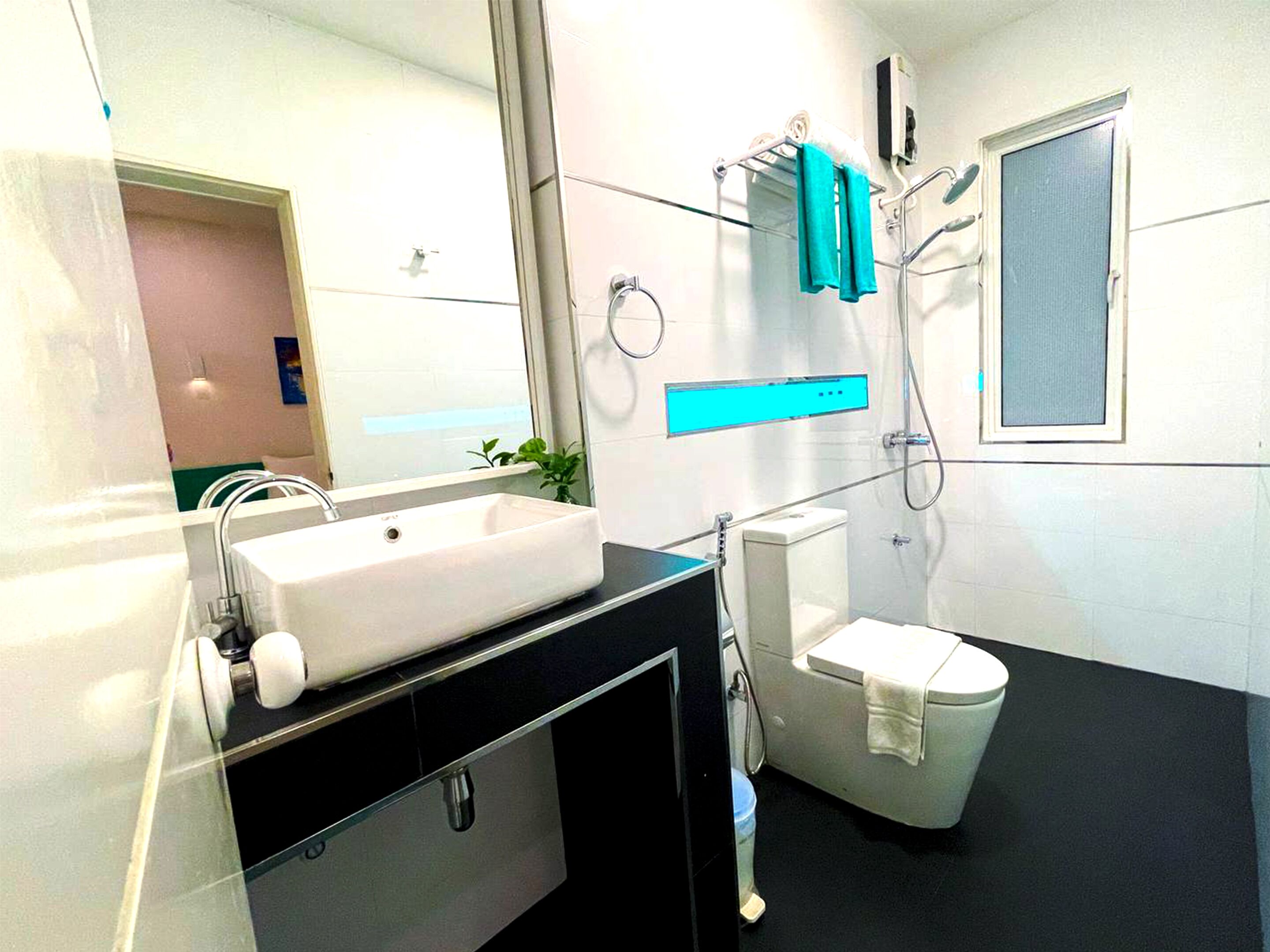 A modern bathroom with a large white sink, a toilet, and a shower.