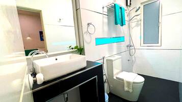 A modern bathroom with a large white sink, a toilet, and a shower.