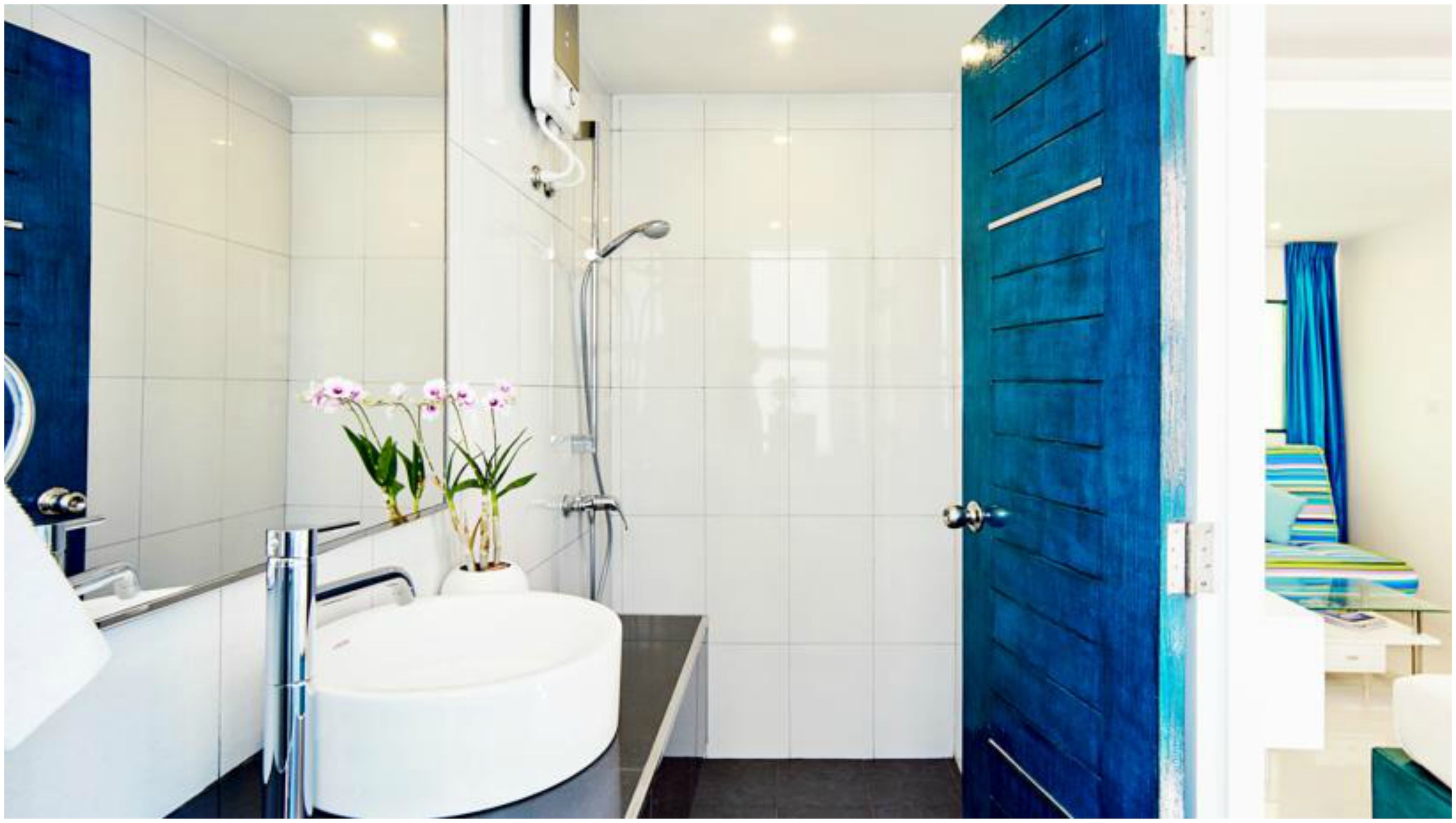 Een moderne badkamer met een witte wastafel, een douche en een blauwe deur.