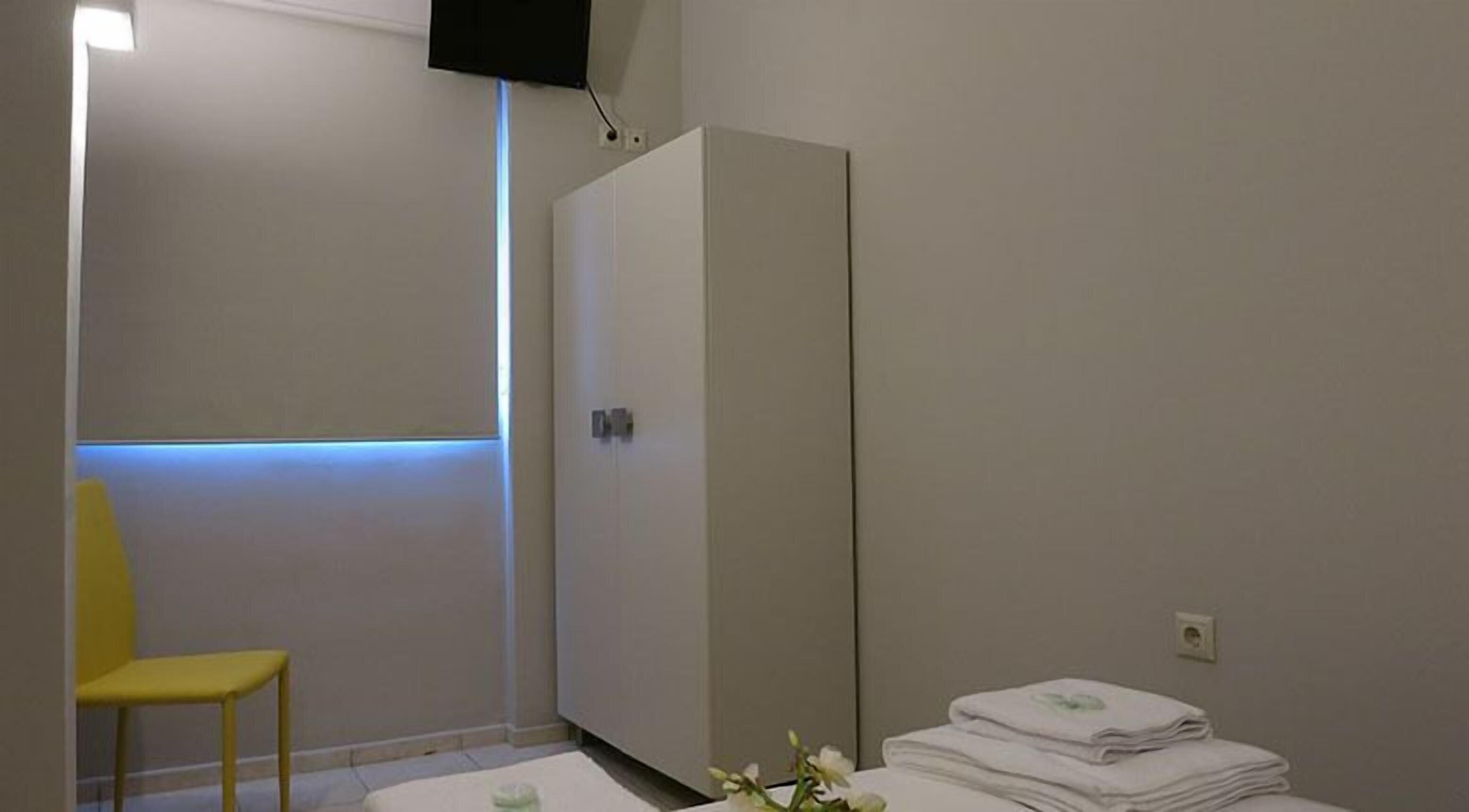 Una habitación con cama, armario, silla y televisor montado en la pared.