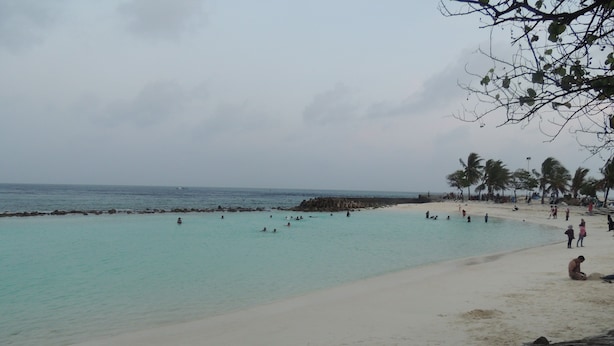A beach with clear turquoise water, a sandy shore, and rocky outcrops. - Off Day Inn Hotel (Malé)