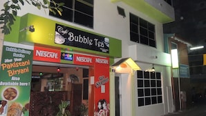 A two-story building with a cafe named 'Bubble Tea' on the ground floor, featuring a green and white facade, and a Nescafe logo on the entrance. - Off Day Inn Hotel (Malé)