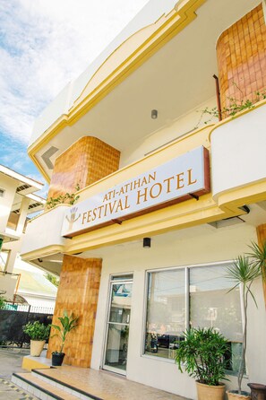 Das Ati-Atihan Festival Hotel mit Schild, Topfpflanzen und einem Balkon.
