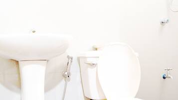 Un baño con lavamanos, inodoro y ducha blancos.