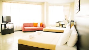 A hotel room with a bed, a sofa, a TV on a stand, and a table with chairs. - Ati-Atihan Festival Hotel (Kalibo)