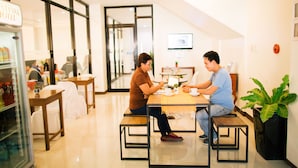 A modern hotel lobby with a glass door entrance, a reception desk, and a seating area with tables and chairs. - Ati-Atihan Festival Hotel (Kalibo)