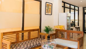 A modern living room with wooden furniture, a glass coffee table, and a ceiling light fixture. - Ati-Atihan Festival Hotel (Kalibo)