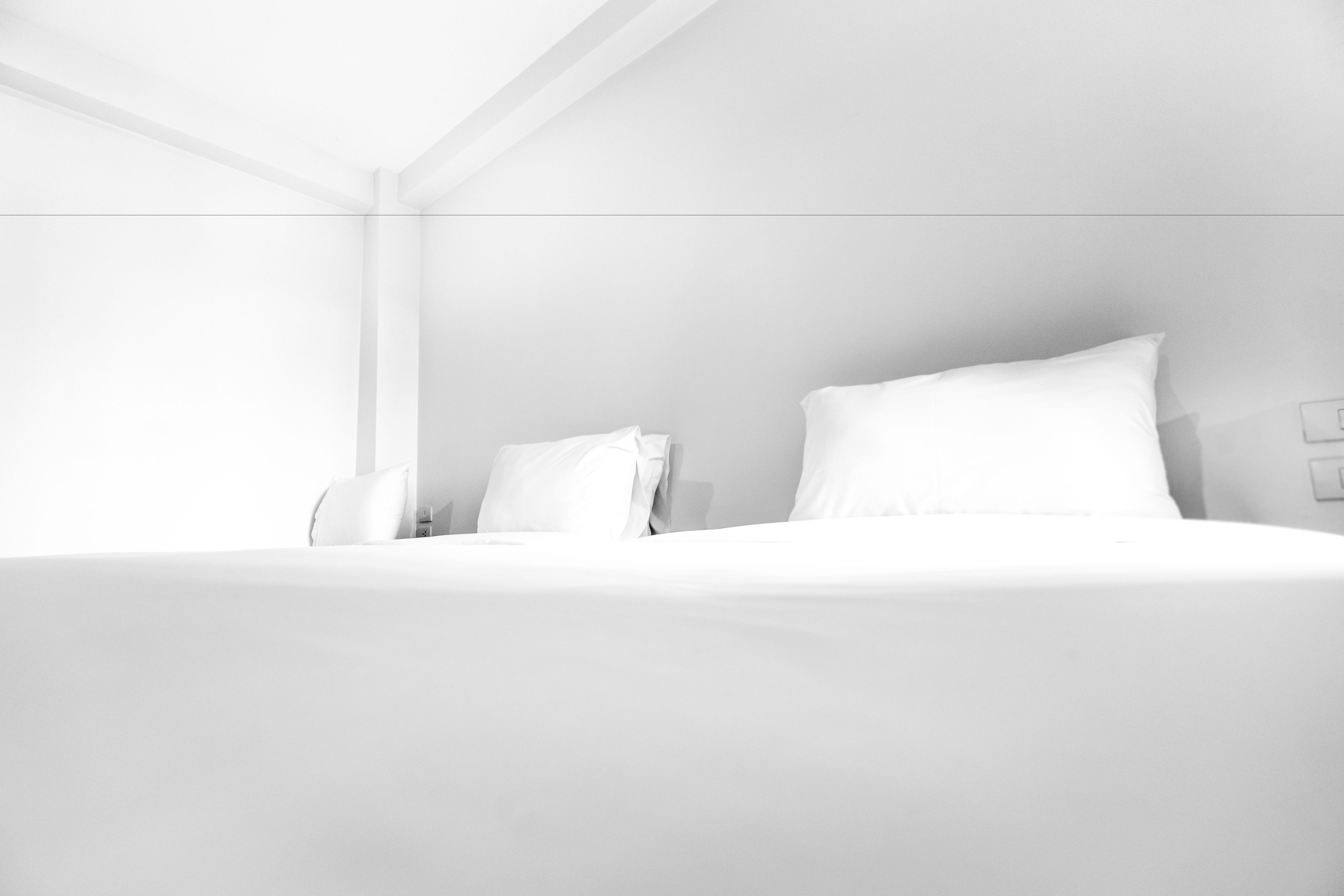 A modern hotel room with a large bed, a bedside table, and a wall-mounted light switch.