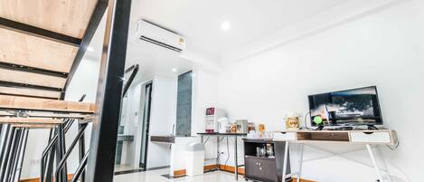 A modern kitchen with a wooden dining table, a built-in TV, and a coffee machine.