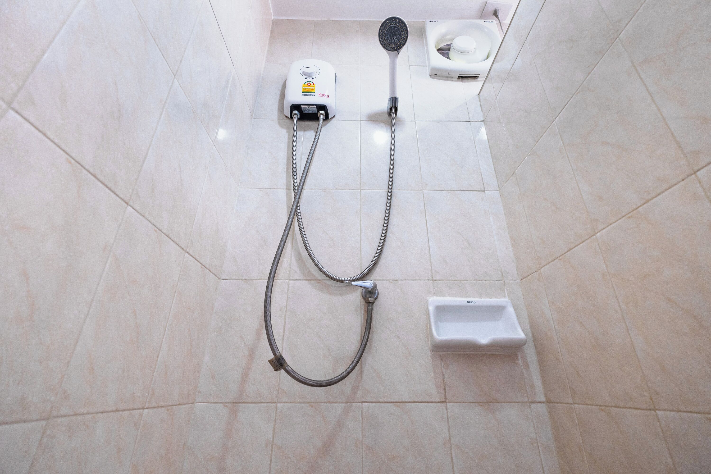 Un baño con ducha, inodoro y un lavabo pequeño y blanco.