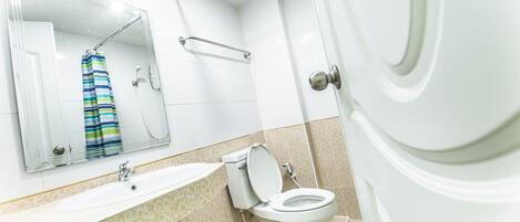 A bathroom with a white sink, toilet, and shower.