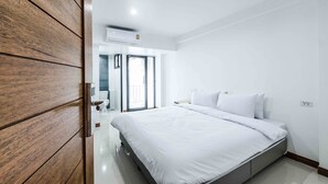 A modern bedroom with a large bed, wooden wardrobe, and a bathroom visible through an open door. - Don Muang Hotel (Bangkok)
