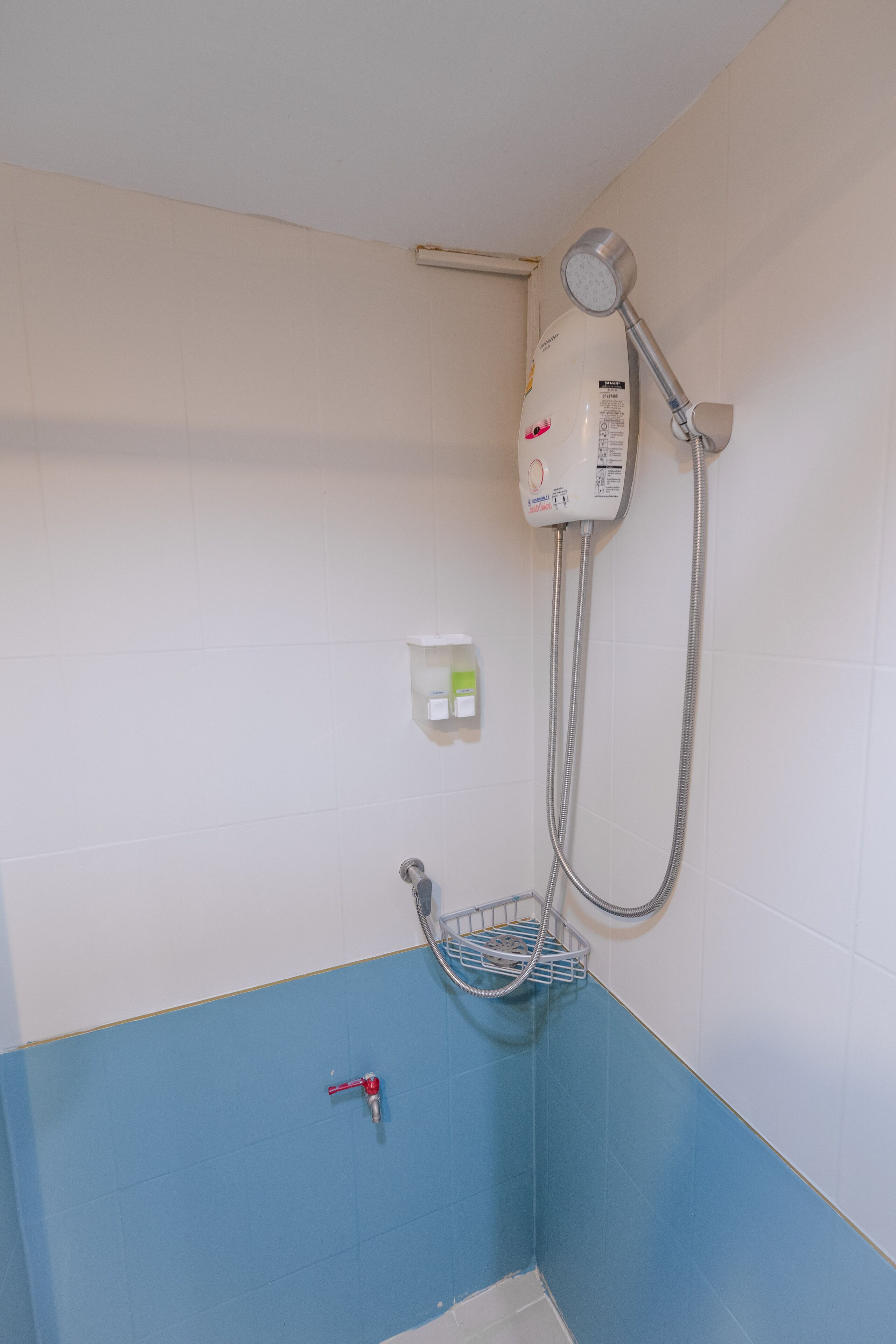 Un baño con ducha, secamanos y dispensador de jabón en la pared.
