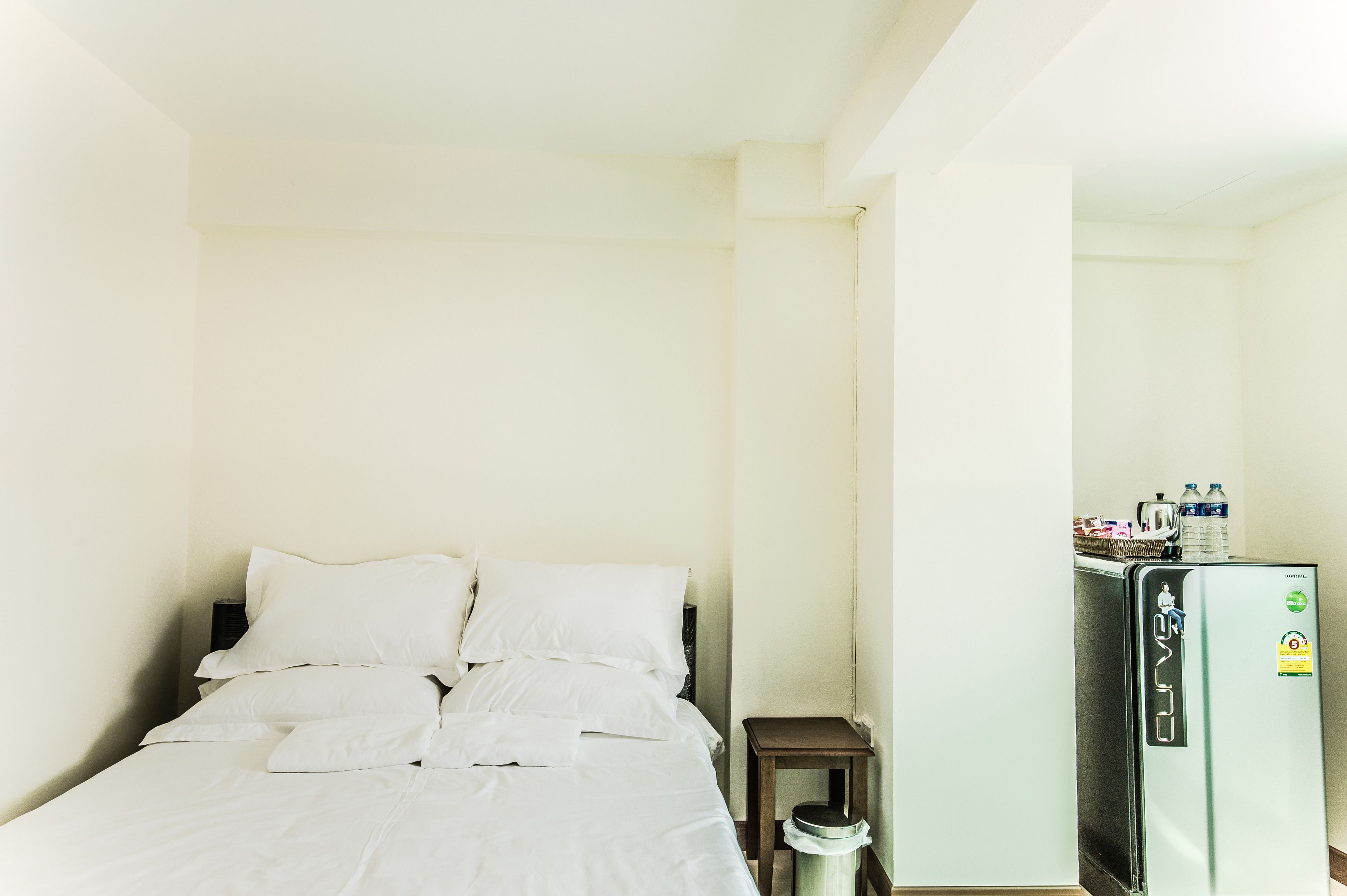 A hotel room with a bed, a small table, and a refrigerator.