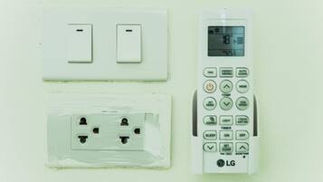 Un enchufe de pared con protector y un control remoto a su lado.