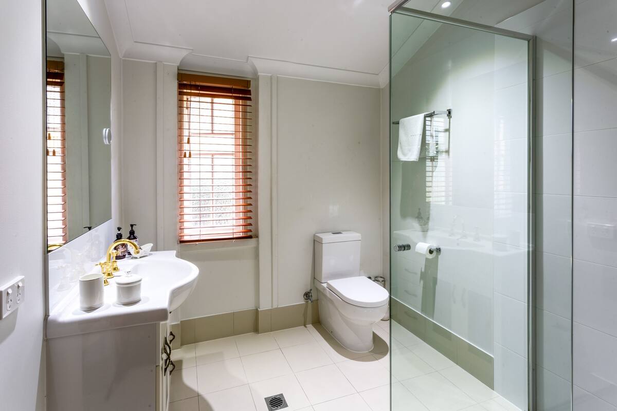 A modern bathroom with a white sink, toilet, and glass shower enclosure.