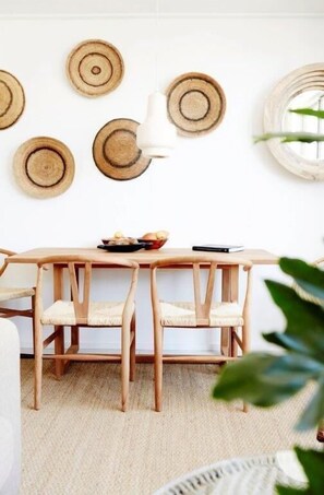 Een eetgedeelte met een houten tafel, vier stoelen en een witte hanglamp.