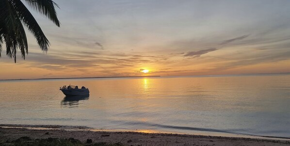 Un bote sobre aguas tranquilas durante el atardecer, bajo un cielo despejado.