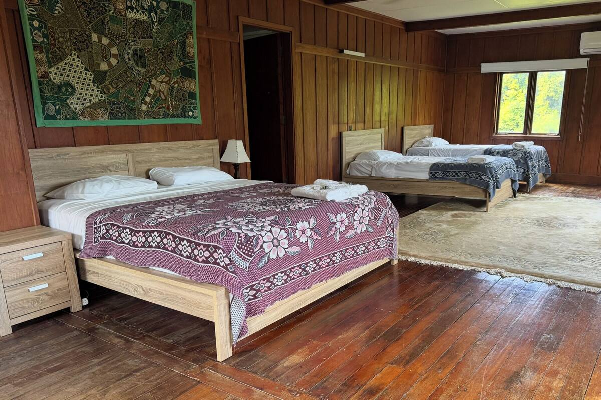 A room with two wooden beds, a large tapestry, and a wooden floor.