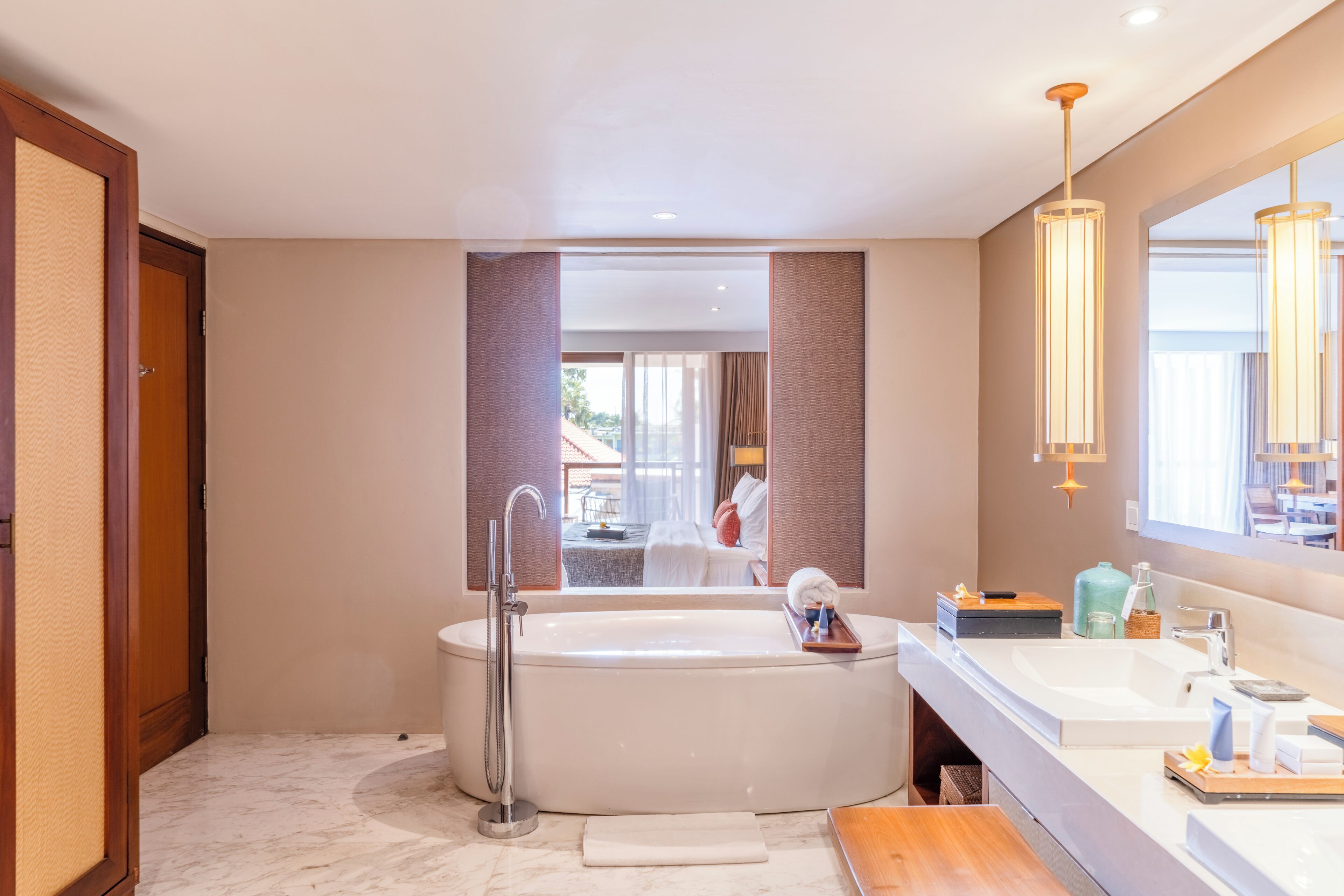 A modern bathroom with a large bathtub, a vanity with a mirror, and a view of the outdoor area.