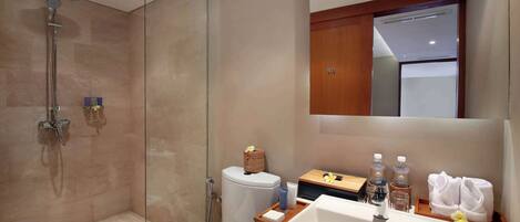 A modern bathroom with a glass-enclosed shower, a toilet, a sink with a mirror, and a wooden vanity.