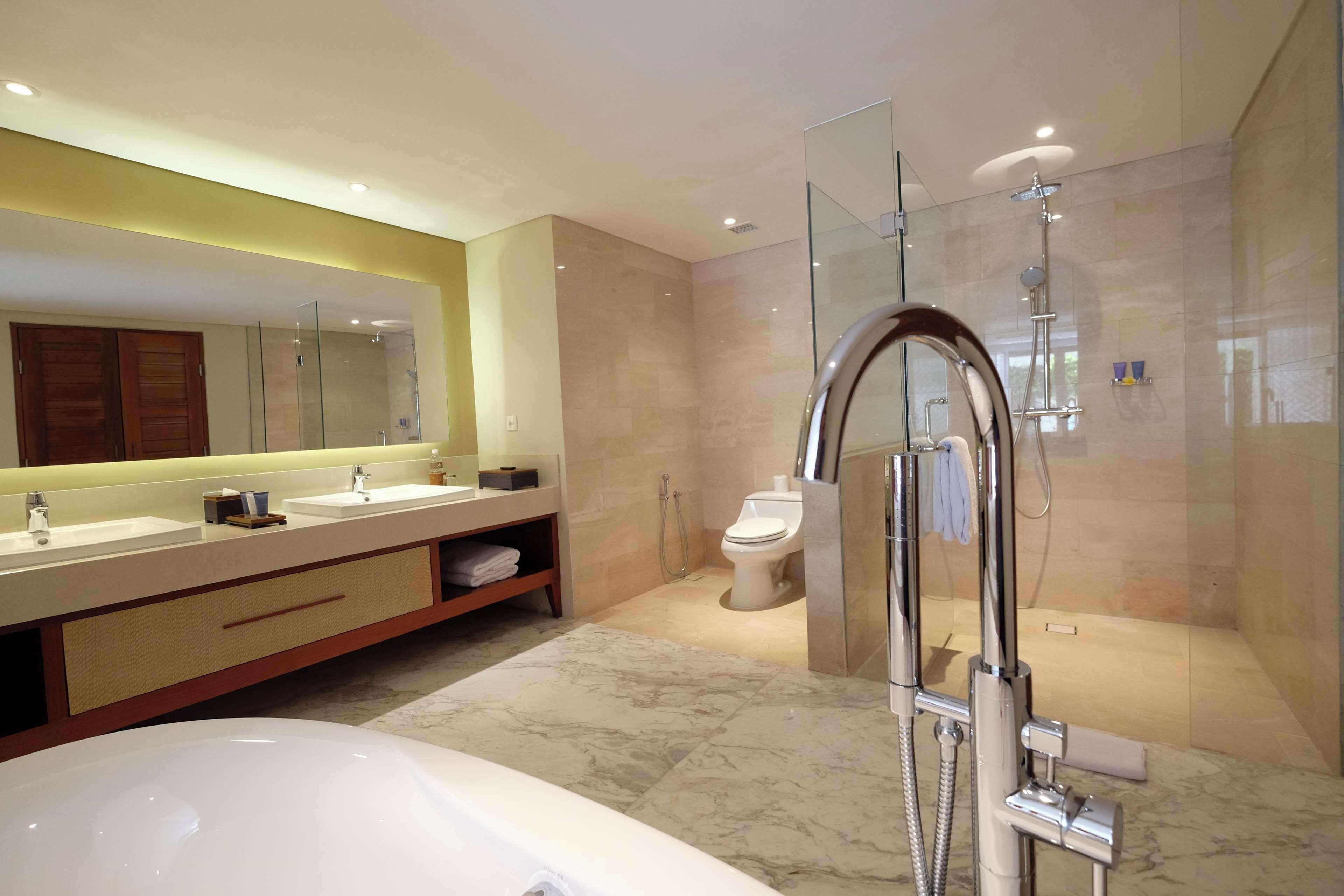 Un baño moderno con ducha de vidrio, un espejo grande y una bañera.