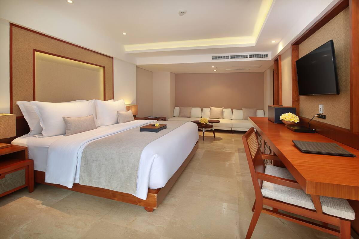 Una habitación de hotel moderna con una cama grande, un sofá, un escritorio y una televisión de pantalla plana.