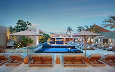 A pool area with lounge chairs and umbrellas, a bar, and a view of the pool.