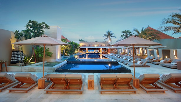 A pool area with lounge chairs and umbrellas, a bar, and a view of the pool. - The Bandha Hotel & Suites (Legian)