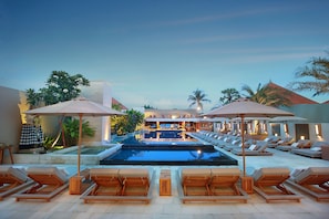 A pool area with lounge chairs and umbrellas, a bar, and a view of the pool.