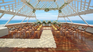 An outdoor wedding venue with a wooden floor, white floral carpet, and a white lattice canopy. - The Bandha Hotel & Suites (Legian)